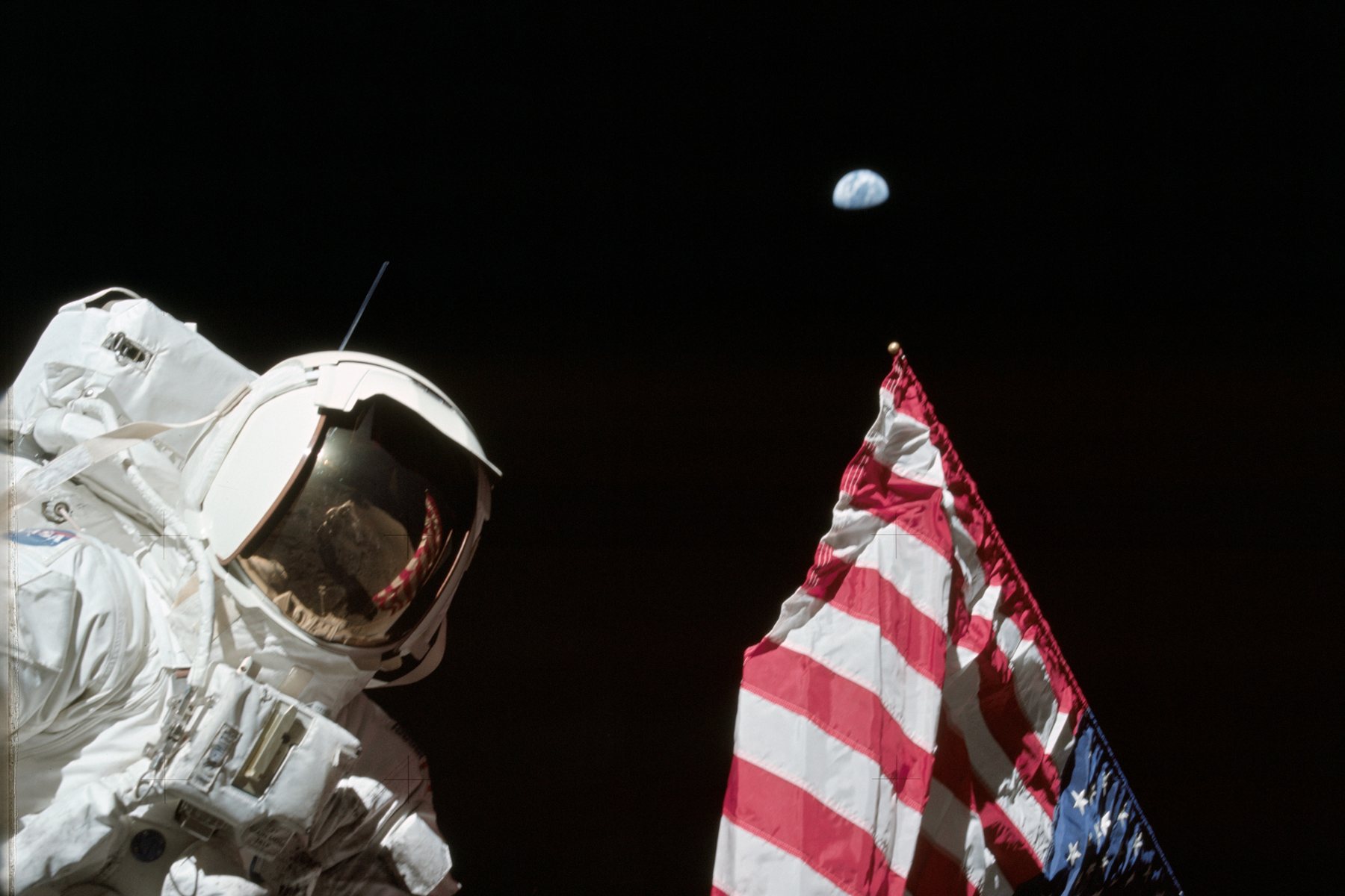Apollo 17 astronaut Harrison Schmitt beside the US flag on the Moon with Earth above the horizon, December 1972