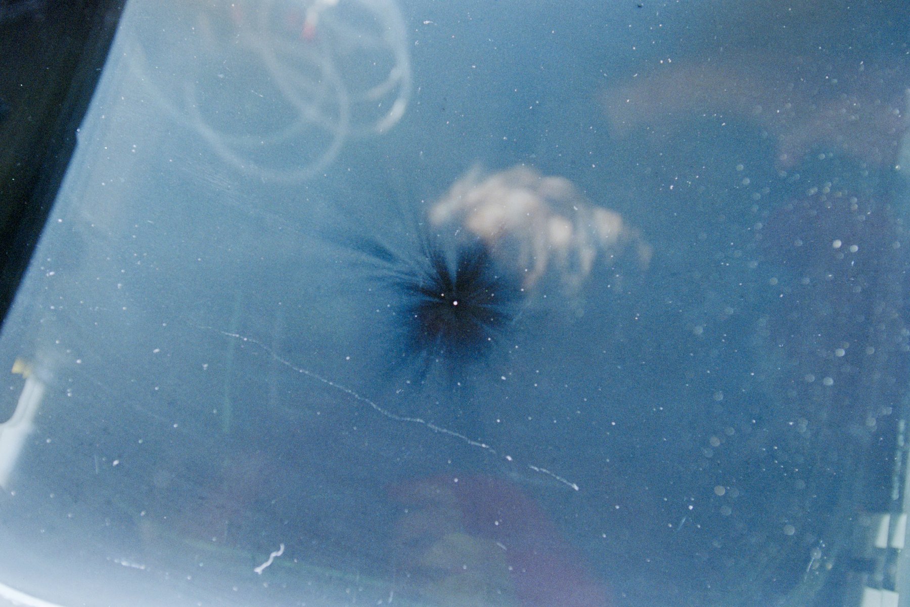 Pit and radiating fracture in a Space Shuttle Columbia flight deck window caused by a high-velocity impact from orbital debris during STS-80, 1996